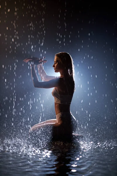 Slim danseuse en sous-vêtements dansant sensuellement sous la pluie, isolée sur noire — Photo