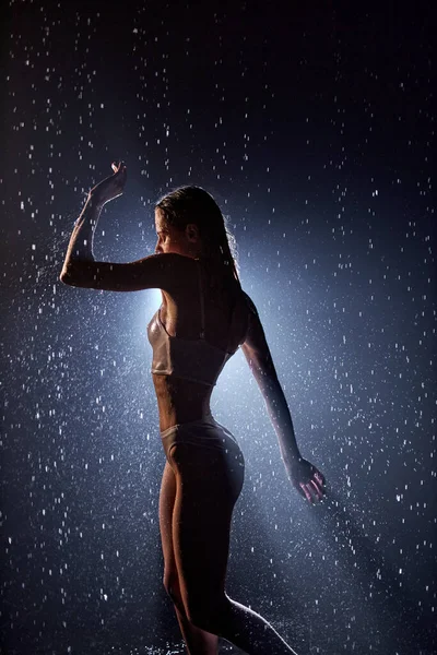 Професійний жіночий виконавець танцює під дощем у темряві, сексуальний і чуттєвий — стокове фото