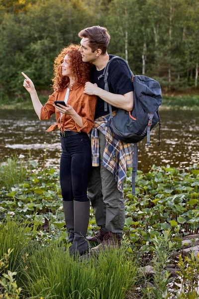 Coppia amichevole uomo e donna godersi la valle della montagna e del fiume, utilizzare lo smartphone — Foto Stock