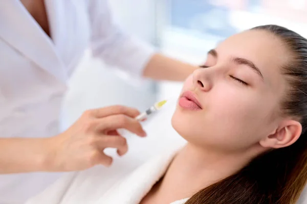 Жіночий косметолог робить ін'єкцію ботокса у жіночих губах, тримаючи шприц — стокове фото