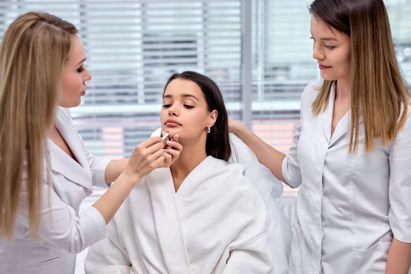 Professional caucasian plastic surgeon drawing contours on female face with pencil — Stock Photo, Image