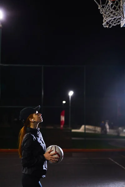 Hermosa Energetic Fitness Mujer en la cancha de baloncesto al aire libre vallada. Por la noche —  Fotos de Stock