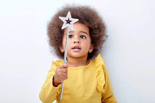 Menina africana bonito segurando varinha mágica, parede do estúdio branco, espaço de cópia — Fotografia de Stock