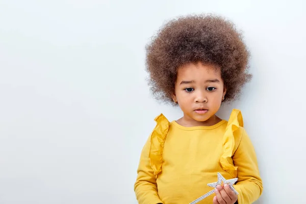 Tranquilo niño diligente de apariencia africana sosteniendo varillas mágicas en las manos, mirando hacia abajo — Foto de Stock