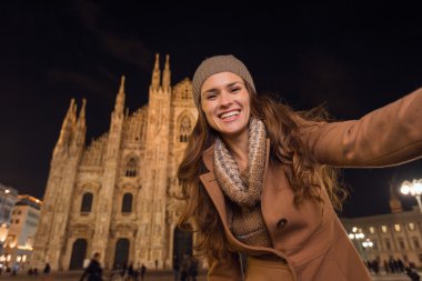 Gülümseyen genç kadın akşam Duomo önünde selfie çekiyor