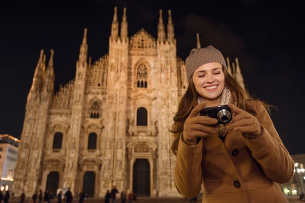 Женщина смотрит на фотографии в фотоаппарате возле Дуомо вечером, Милан — стоковое фото