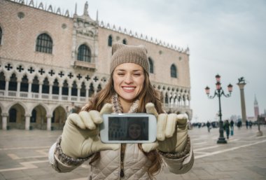 Woman tourist taking selfie with cell phone on St.Mark's Square
