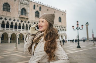 Gülümseyen kadın turist St Mark Meydanı'nda cep telefonu konuşuyor