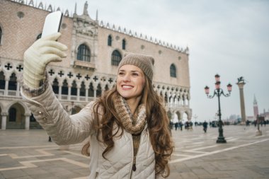 Woman tourist taking selfie with cell phone on St.Mark's Square