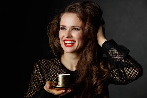 Sonriendo con cabello castaño sosteniendo taza de café sobre fondo oscuro —  Fotos de Stock