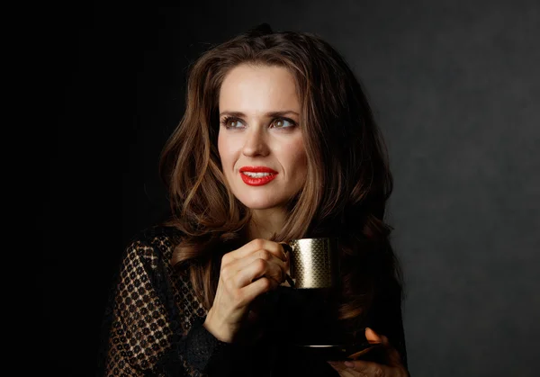 Donna con tazza di caffè guardando sullo spazio copia, sfondo scuro — Foto Stock