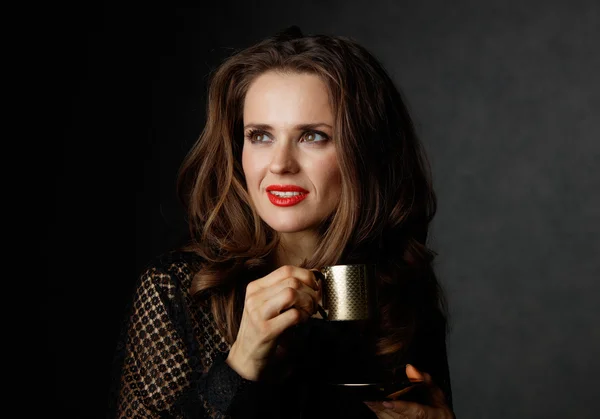 Woman with cup of coffee looking on copy space, dark background — Stock Photo, Image