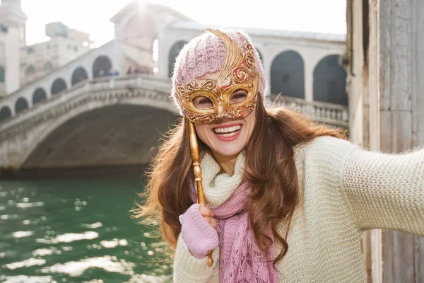 Mujer sonriente con máscara de Venecia cerca del puente de Rialto tomando selfie —  Fotos de Stock