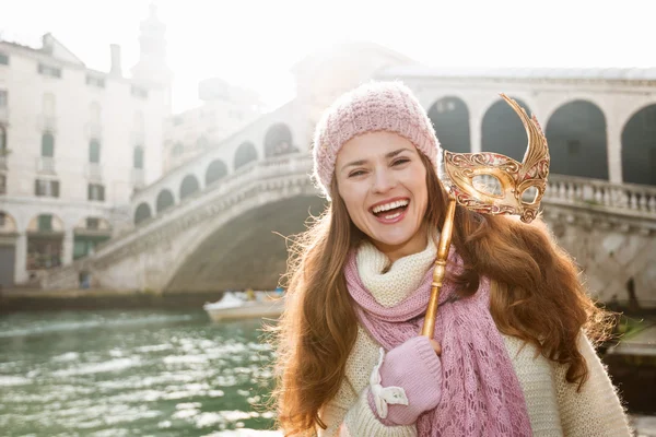 Mujer sonriente sosteniendo la máscara de Venecia en la parte delantera del puente de Rialto —  Fotos de Stock