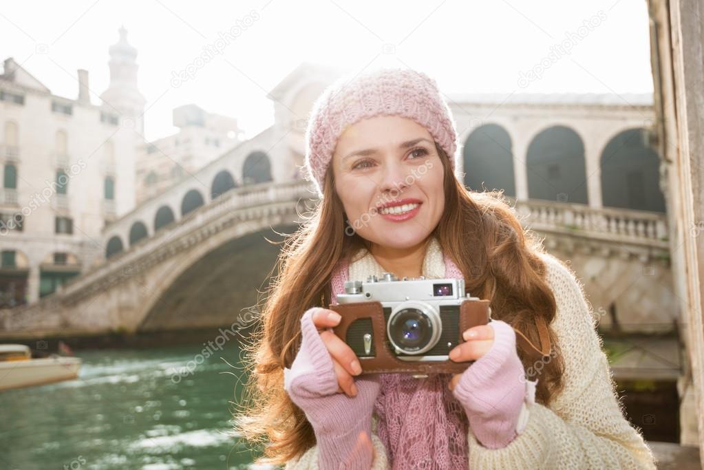Happy woman tourist with retro photo camera near Rialto Bridge