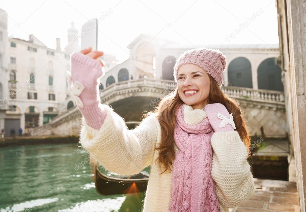 Happy woman tourist taking selfie in front of Rialto Bridge