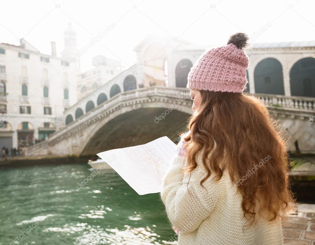 Woman tourist with map near Rialto Bridge. Seen from behind