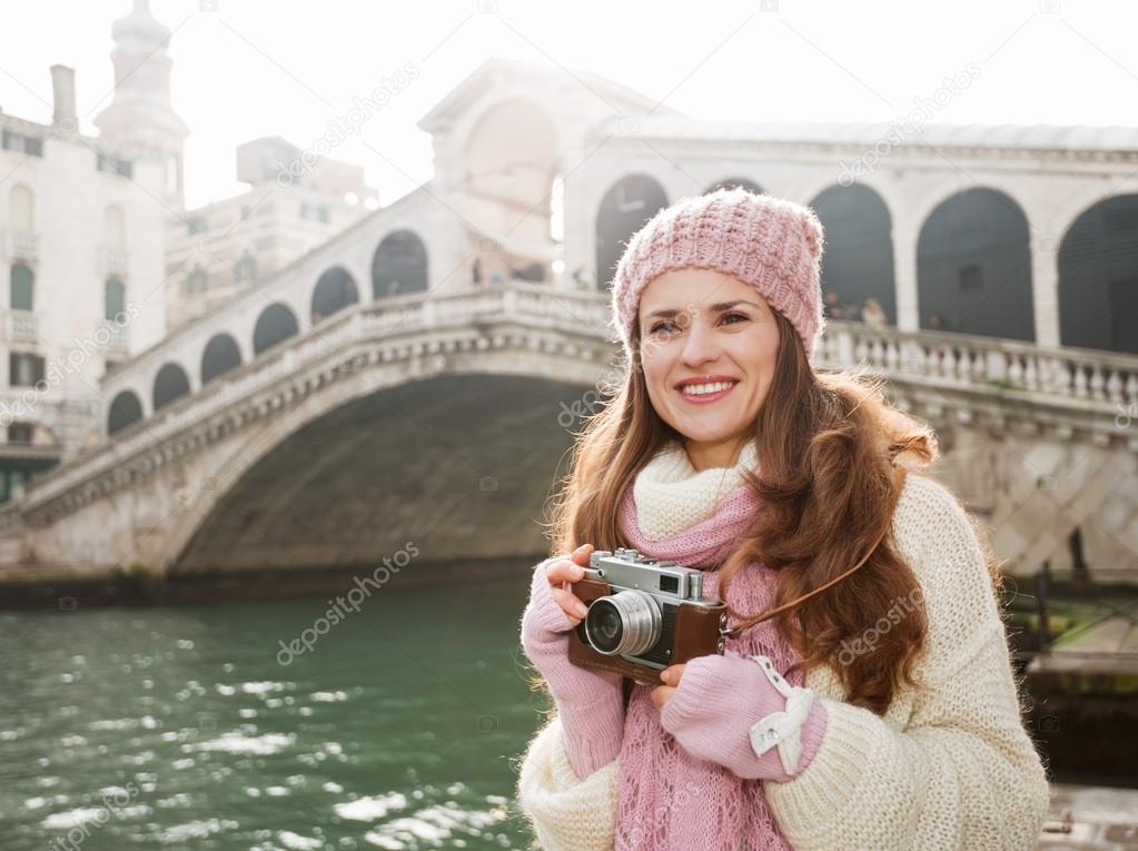 Woman tourist with retro camera in the front of Rialto Bridge
