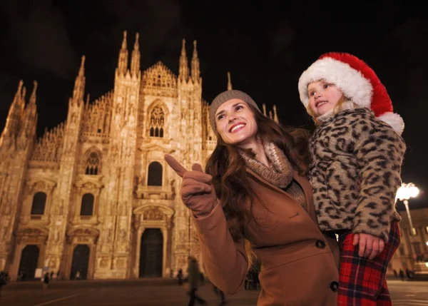 Mutter zeigt Tochter mit Weihnachtsmütze auf etwas, Mailand — Stockfoto