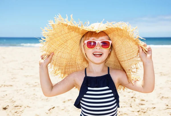 Lachende meisje in badpak en grote stro hoed op een wit strand — Stockfoto