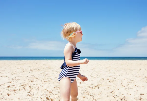 Chica feliz en traje de baño a rayas en una playa blanca mirando a un lado — Foto de Stock