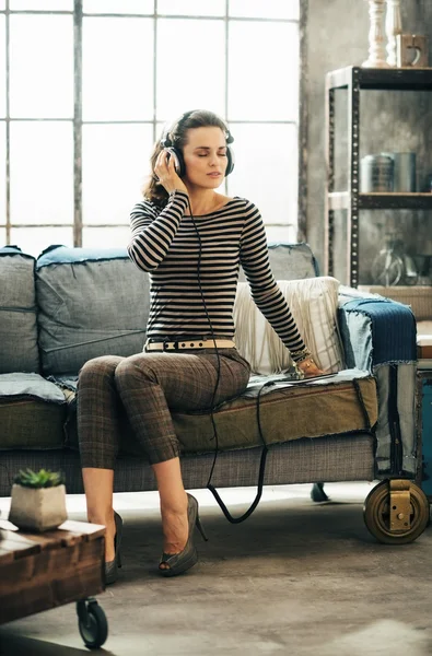 Mulher ouvindo música através de fones de ouvido no apartamento loft — Fotografia de Stock