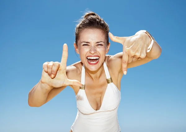 Uśmiechnięta kobieta w strój kąpielowy na plaży kadrowanie z rąk — Zdjęcie stockowe