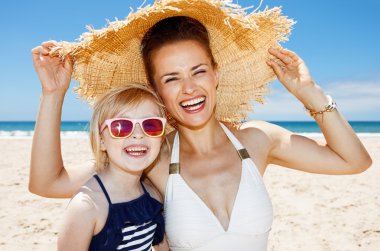 Anne ve kızı kumlu Plajı'nda büyük hasır şapka altında gülümseyen