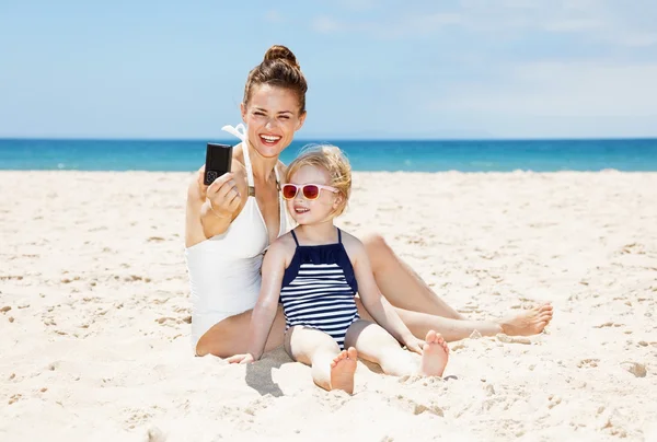 微笑的母亲和女儿带相机在海滩拍照 — 图库照片