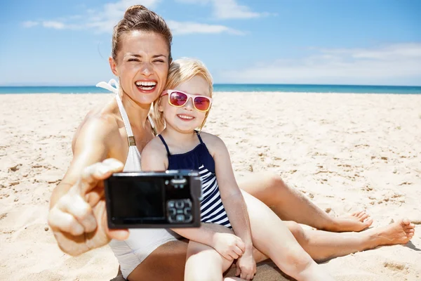 Mãe feliz e criança tomando selfies com câmera na praia de areia — Fotografia de Stock