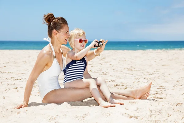 Feliz madre e hija en trajes de baño tomando fotos en la playa —  Fotos de Stock