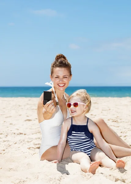 Mutlu anne ve kızı plajda kamera ile selfies alarak — Stok fotoğraf