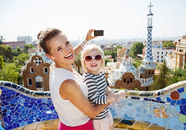 Smiling mother and baby taking photos with camera at Park Guell — Stock Photo, Image