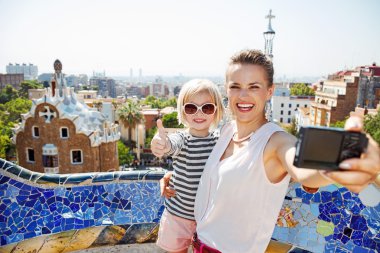 Anne ve bebek ile Park Guell kameraya selfie alarak gülümseyen