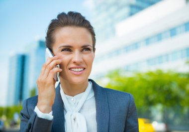 Mutlu bir iş kadını office bölgesinde smartphone konuşuyor