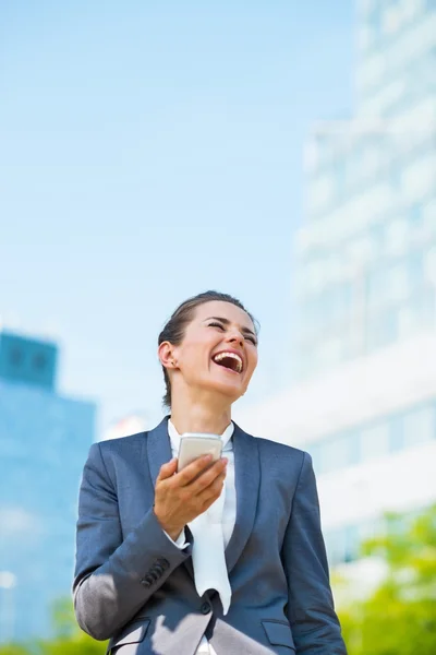 Laughing business woman with smartphone in office district — Stock Photo, Image