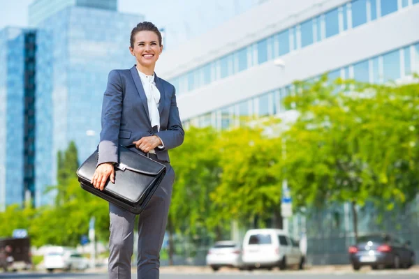 Happy business woman with briefcase in modern office district — Stock Photo, Image