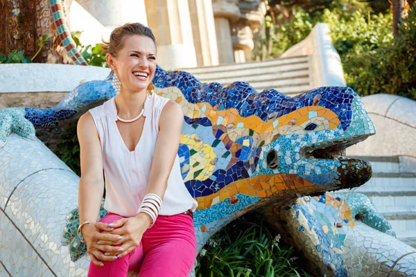 Donna sorridente seduta vicino al drago mosaico a Park Guell, Spagna — Foto Stock