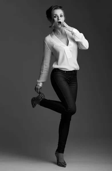 灰色の背景に対して靴を調整する驚きのエレガントな女性 — ストック写真