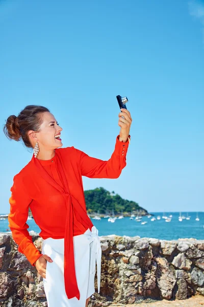 Woman taking photo with digital camera in front of lagoon — Stockfoto