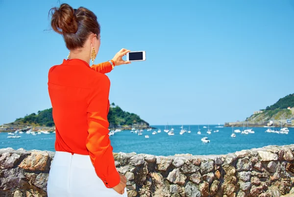Sett bakifrån kvinna tar foto med smartphone av lagunen. — Stockfoto