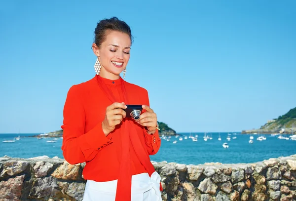 Happy woman in front of lagoon checking photos in digital camera — Stock Photo, Image