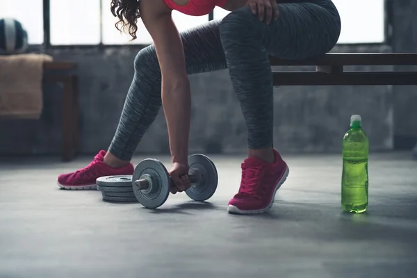 Closeup on fitness woman taking dumbbell from the floor in gym — Stock Photo, Image