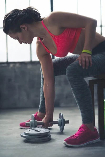 Fitness nő vesz súlyzó a padlóról a városi tetőtéri tornaterem — Stock Fotó