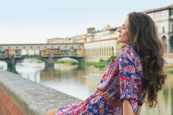 Relaxado mulher de vestido sentado no dique perto de Ponte Vecchio — Fotografia de Stock