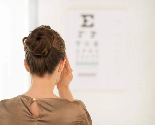 Visto da dietro donna testare la visione con grafico Snellen — Foto Stock