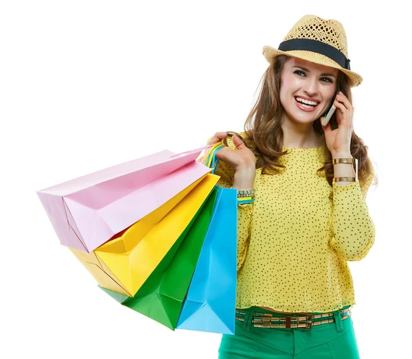 Mulher sorridente de chapéu com sacos de compras falando celular — Fotografia de Stock