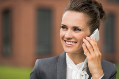 Gülümseyen iş kadın konuşmak smartphone bina ofisinin