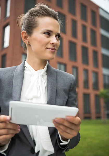 Femme d'affaires avec tablette PC près de l'immeuble de bureaux regardant de côté — Photo