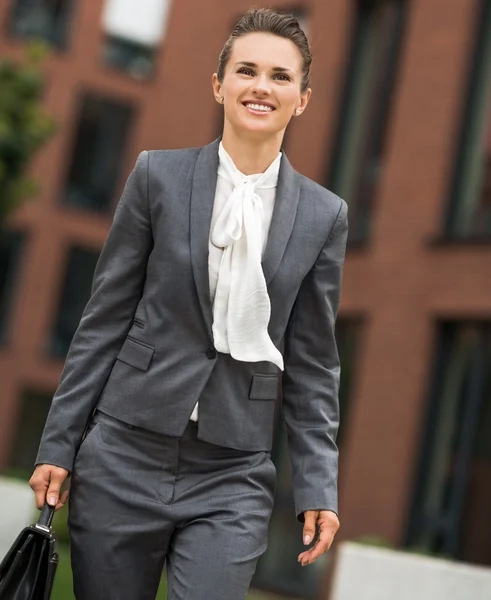 Heureuse femme d'affaires avec mallette marchant dans le quartier des bureaux — Photo